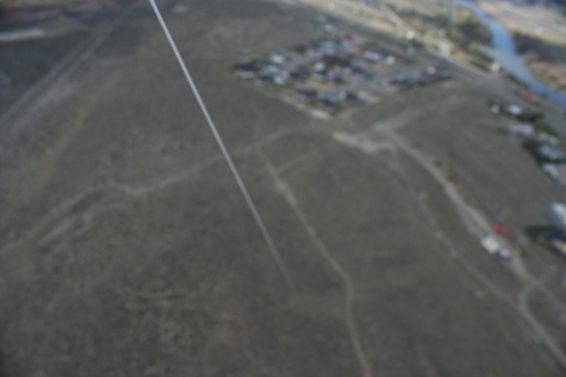 Blurry shot of string, houses and sagebrush below camera